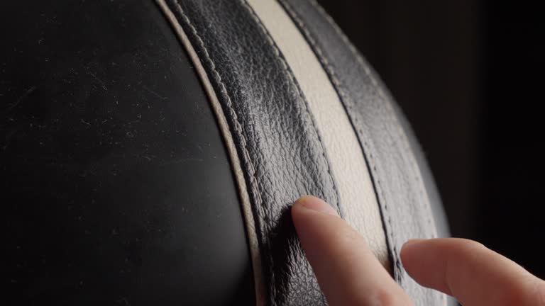 Close-up of a hand running fingers over textured black leather, emphasizing touch and detail