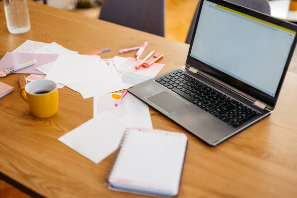 Laptop and collage papers on the table in the kitchen.