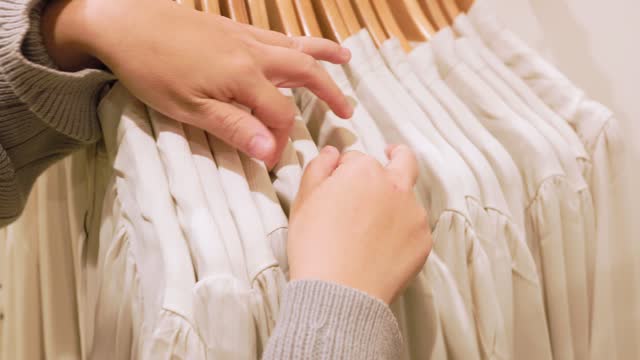 CU Women's hands looking through clothes rack