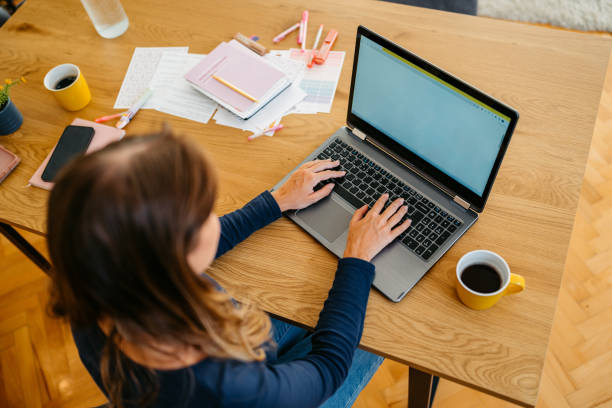 istock Young Woman Working On A Laptop At The Kitchen Table 2132132323