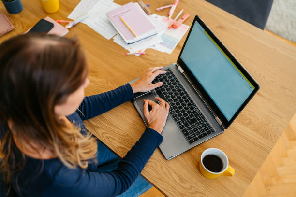 istock Young Woman Working On A Laptop At The Kitchen Table 2132132855
