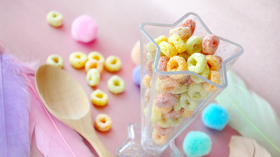 Colorful fruit loops cereal for breakfast on sweet pink background