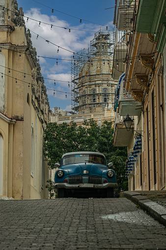 An old retro car on a narrow street in Havana against the backdrop of a colonial cathedral.