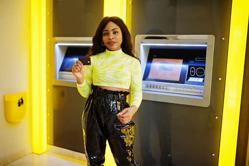 African american woman hold credit card after withdrawing money from a cash machine, ATM concept.
