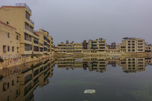 Residential buildings surrounding Talkatora Lake with a single Kite floating on the surface of the water in Jaipur, Rajasthan
