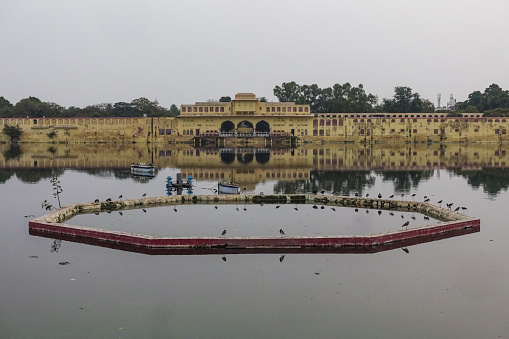 Badal Mahal a historical landmark and the residential buildings with its reflections on the water surrounding Talkatora Lake in Jaipur, Rajasthan