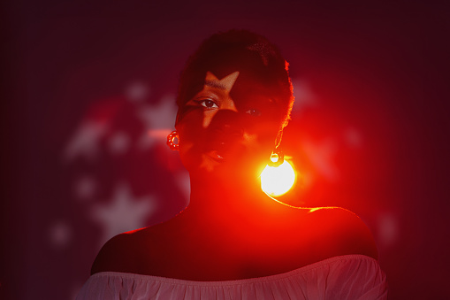 Confident African, attractive woman with a star symbol on her face in red light. Authentic and successful in the future concept.