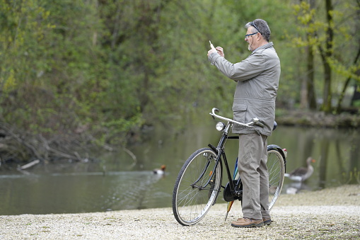 Legnano, Italy - April 01, 2024: man take a photo Sith smartphone in front of a pond
