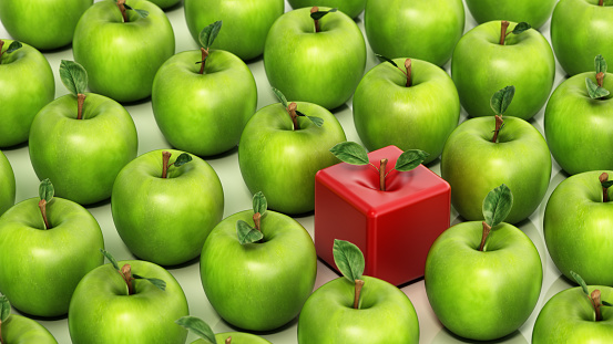A red cube shaped apple is placed in the center of the image, surrounded by a variety of green apples. Uniqueness concept.