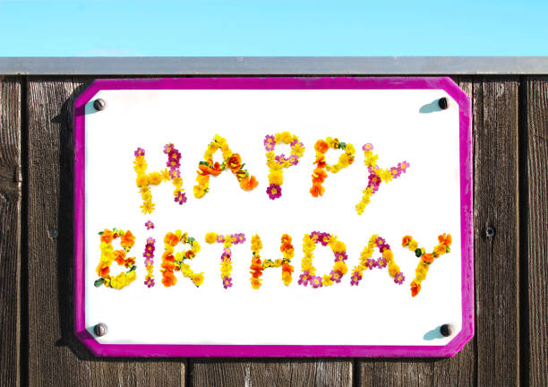 happy birthday sign made of yellow pink red and orange flowers collage, enamel, metal or pottery sign, wooden wall. frame, turquoise sky - emaille-auf-platte stock-fotos und bilder