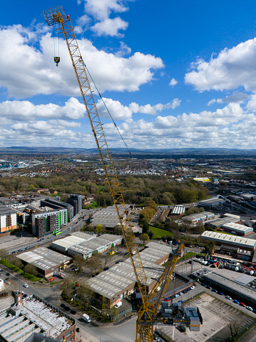 An aerial photograph of the top of a mechanical crane which is taking a break from work over the Easter period. The view looks out across the suburbs of Manchester on Northwest England. The photograph was produced on a beautiful sunny day.