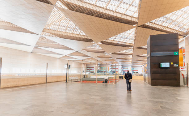 a man is walking at the Zaragoza train station. The station is very large and has a lot of empty space