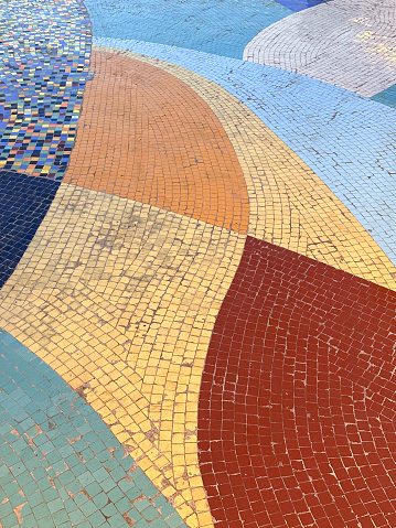 Stock photo showing close-up view of a randomised mosaic wall decoration that has been created by using a mixture of broken pottery. These smashed pieces have been carefully laid out on some evenly spread tile adhesive, taking care to keep them all level, being grouted once dry and set in place.