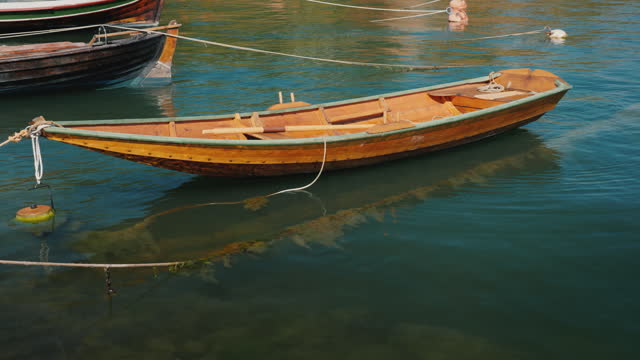 A small wooden fishing boat rocks on waves near the shore