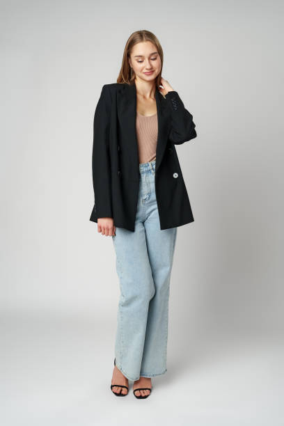 istock Young Woman Wearing Black Jacket and Jeans posing on gray background studio shot . 2132255492