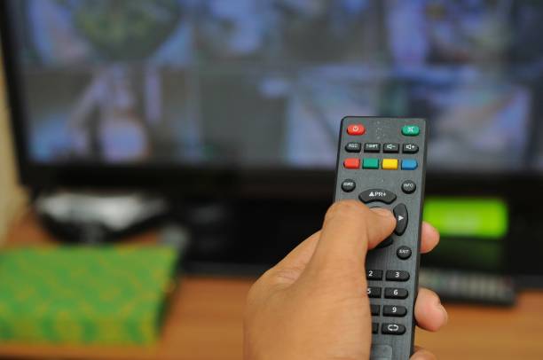istock a man's hand holding a tv remote, bokeh background 2132273468