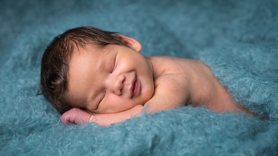 Newborn baby in the first days of life. Cute little newborn boy on a blue soft blanket