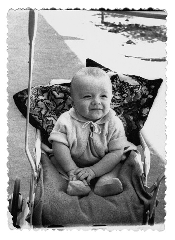 Vintage photo of a boy in a stroller. The child smiles. Photo from 1961.