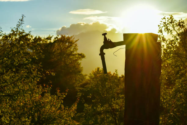 An old faucet in the countryside, the sun setting in the background