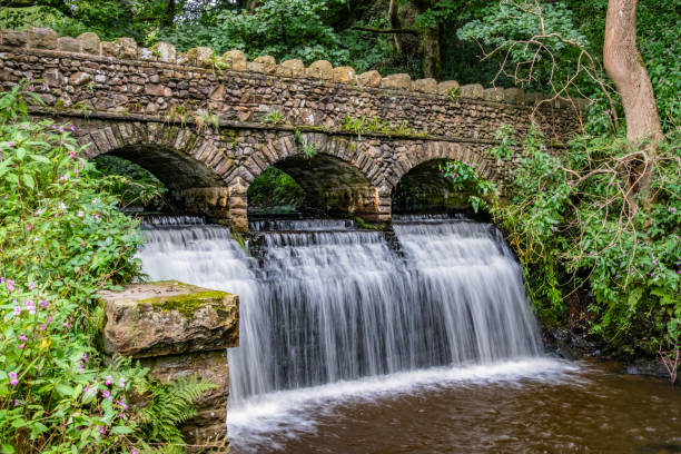 A scenic view of an historical three arch stone bridge with waterfall.