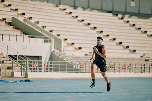 Fitness, stadium and man running on a track training for a race, marathon or olympic competition. Sports, runner or athlete doing a cardio exercise for endurance, motivation and speed on a race track