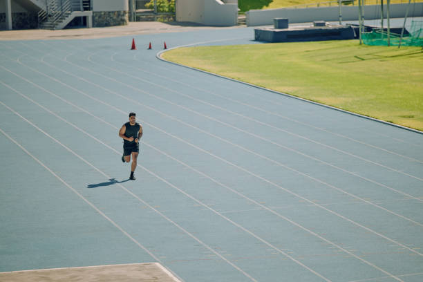 Running, exercise and athlete man at stadium for exercise, workout and training for race, marathon or sports competition with speed and agile performance. Male running on track for fitness and energy