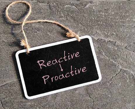 Chalkboard with text written PROACTIVE and REACTIVE , different traits - one focuses on eliminating problems before happened and one approach is based on responding to events after they have happened.
