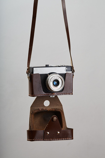 Old-fashioned professional vintage SLR analog 35mm film camera hanging in front of a white background