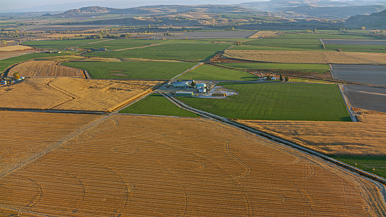 Aerial view of farmland with warehouse in rural area on sunny day in Idaho, USA.