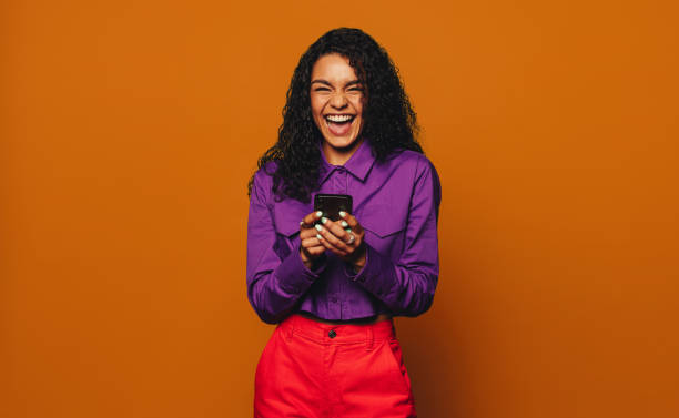 istock Smiling woman using phone on orange background 2132418630