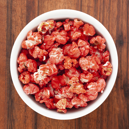 Top view of white bowl full of fresh red dyed popcorn