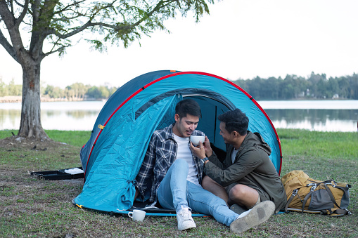 Asian homosexual couple spending their free time on holiday Camp to relax, cook and enjoy the outdoors together..