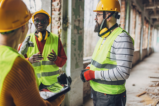 Diverse group of construction workers engage in a discussion within an unfinished building