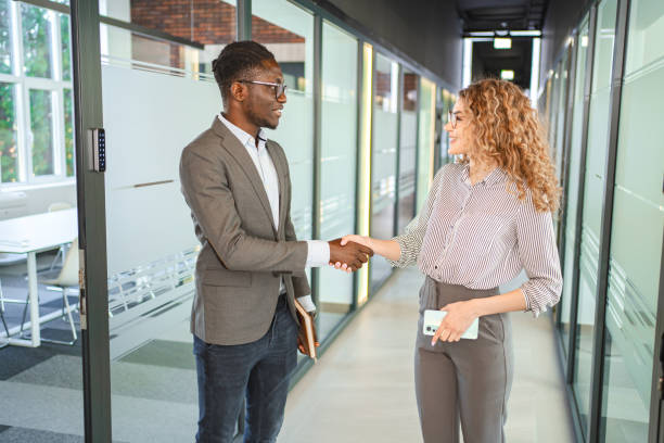 istock Two multiracial business colleagues shaking hands at the office corridor 2132567593