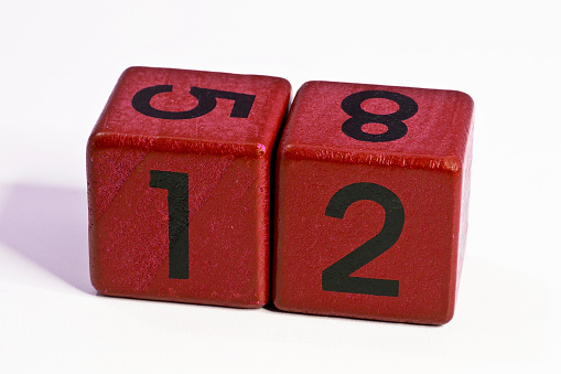 Number twelve written on a red wooden cube of a calendar date.