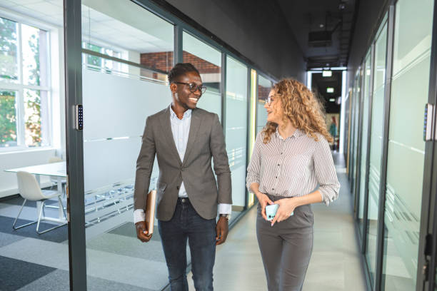 istock Two multiracial business colleagues talking while walking through the office corridor 2132590889