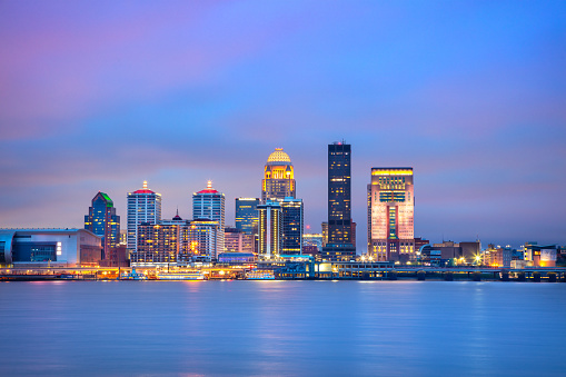 Cityscape image of Louisville, Kentucky, USA downtown skyline with reflection of the city the Ohio River at spring sunrise.