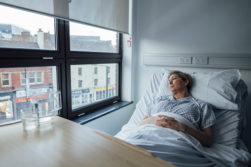A wide-angle side view of a female undergoing treatment for Breast Cancer. She is lying on the bed with her eyes closed resting after treatment. She is in a hospital in Newcastle upon Tyne in the North East of England.

Videos are available for this scenario