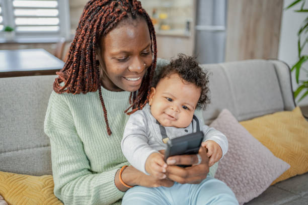 istock Black mother using mobile phone with her baby son at home 2132628165