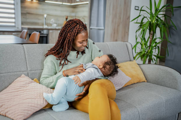 istock Black mother playing with her baby son at home on a sofa 2132629212