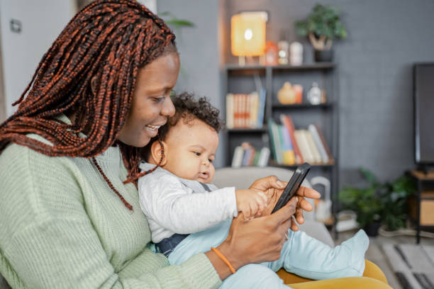 istock Black mother using mobile phone with her baby son at home 2132640201