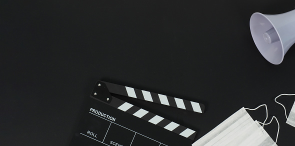 Black clapper board or movie slate and face mask ,magaphone on black background.it use in video production and movie industry.