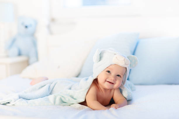 istock Baby boy in blue towel on white bed 2132668372