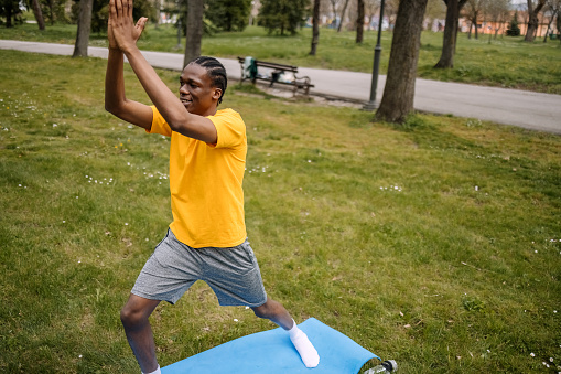 Generation Z black man having yoga practice in public park