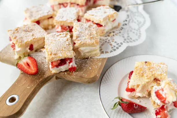 Strawberry sponge cake with delicious cream filling and chopped strawberries and almond topping. Served ready to eat on a platter.