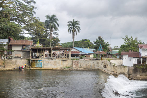 Bukit Lawang, Sumatra, Indonesia - January 19th 2024:  Small cascade in the middle of a village and people washing their clothes in the river