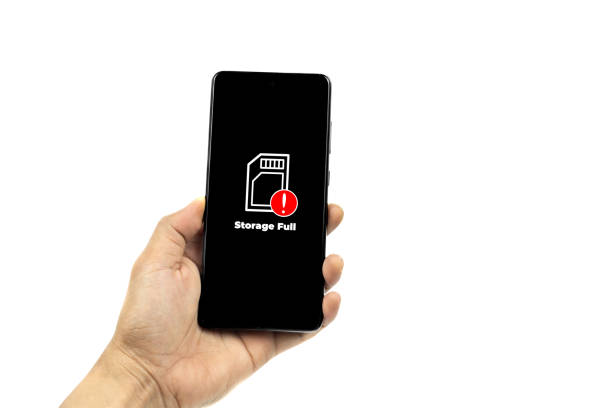 istock Cellular Problems Concepts. Man hand holding smart phone with full storage icon on screen isolated on white background. All screen graphics are made up. 2132740110