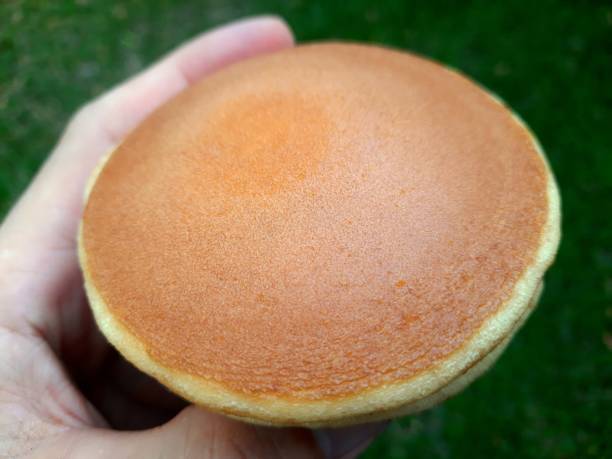 Hand holding Dorayaki breads - green background.