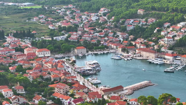 AERIAL: Scenic drone view of the buildings and yachts in the lush bay of Hvar.