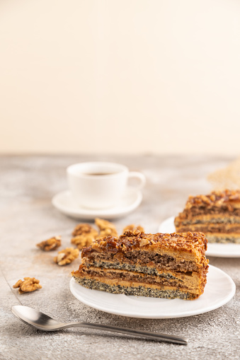 Walnut and hazelnut cake with caramel cream, cup of coffee on brown concrete background. side view, selective focus